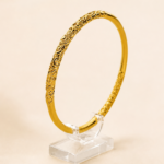 Aurone Scrolling Vine Pattern Bangle centered on a transparent acrylic jewelry stand