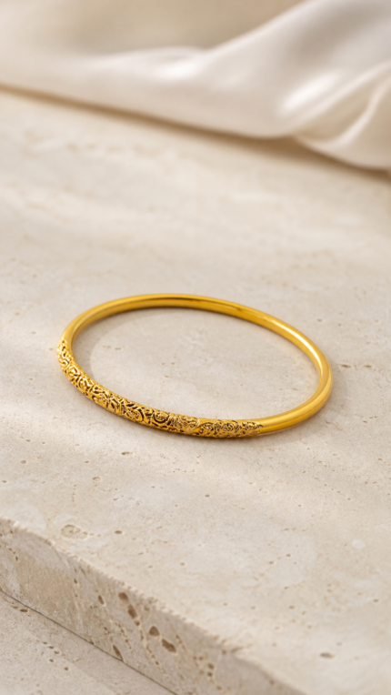 Aurone Scrolling Vine Pattern Bangle lying naturally in a minimalist ivory scene